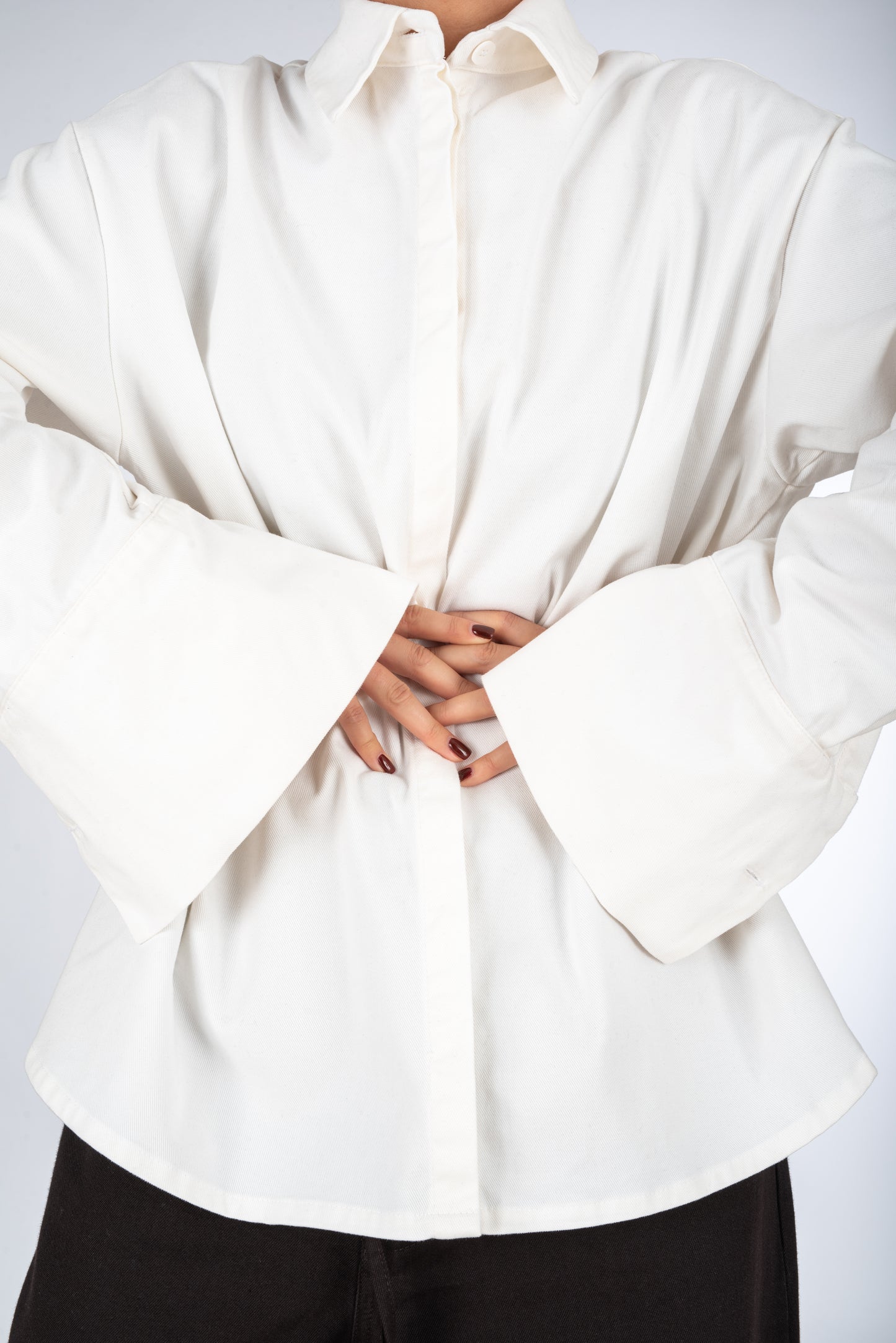 Lifestyle shot of the front of a thick white women's shirt, highlighting the sleeve cuffs, minimal design.