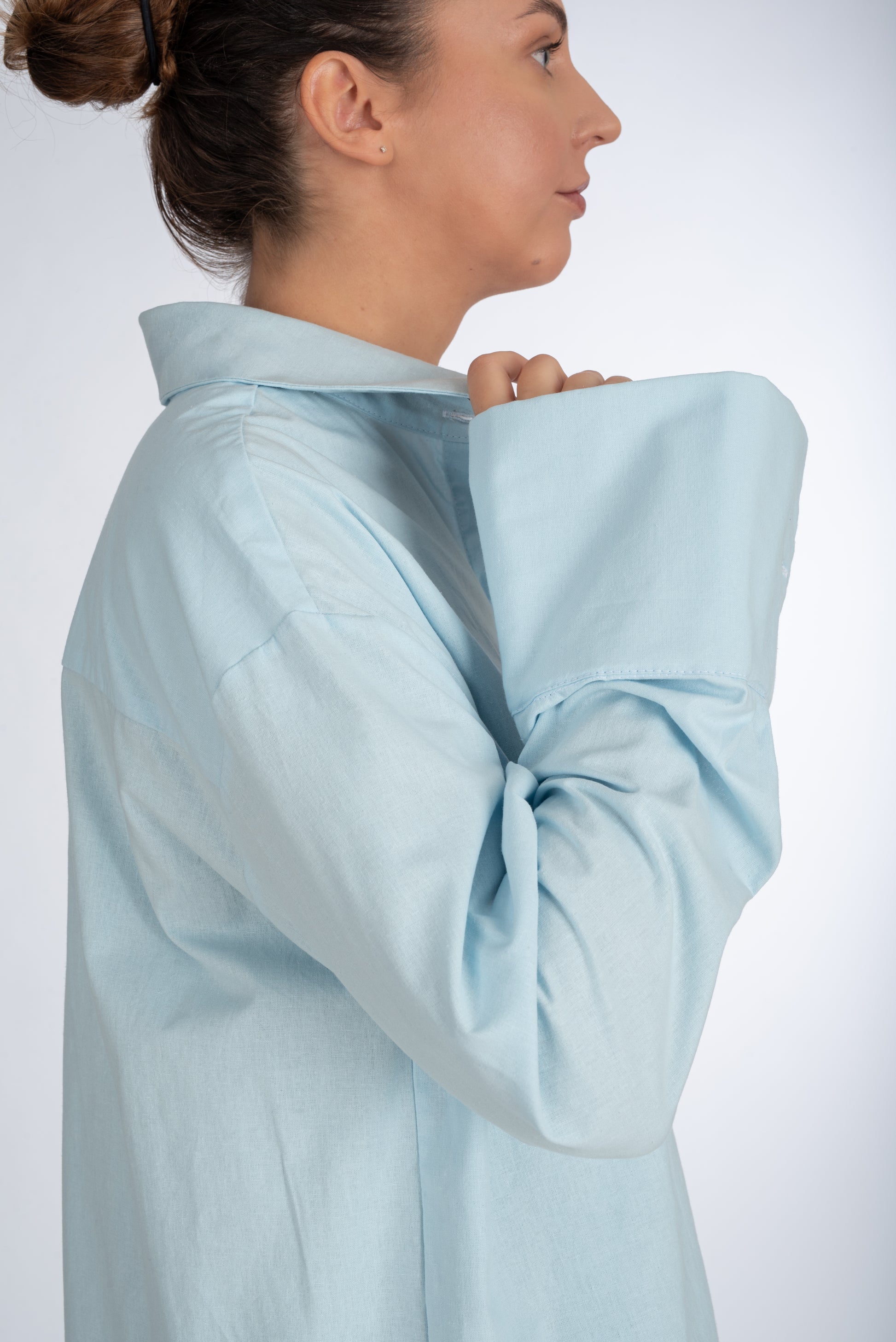Side view of a baby blue women's shirt, emphasizing the size and fit of the sleeve cuff with precision tailoring and reinforced structure.