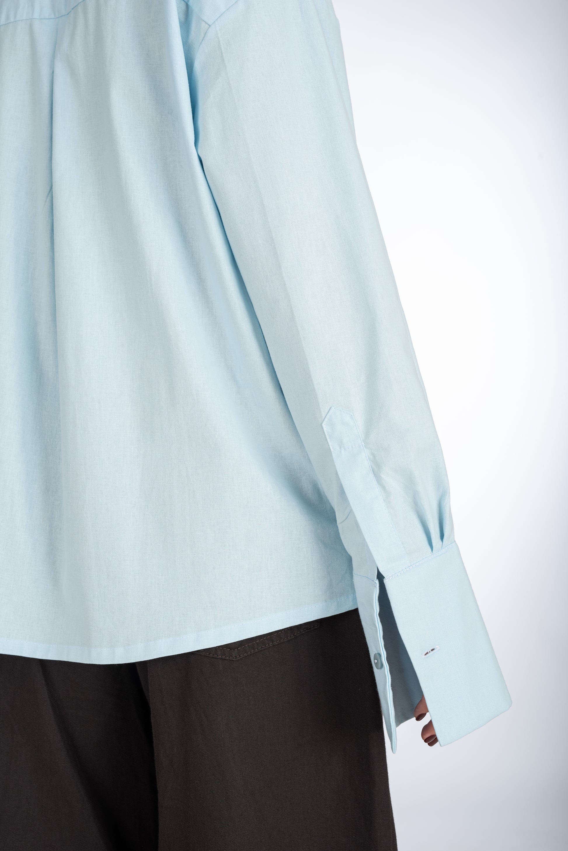 Close-up of the embroidered logo on the sleeve of a baby blue straight-fit women's shirt, showcasing the tailored cuff and reinforced fabric.